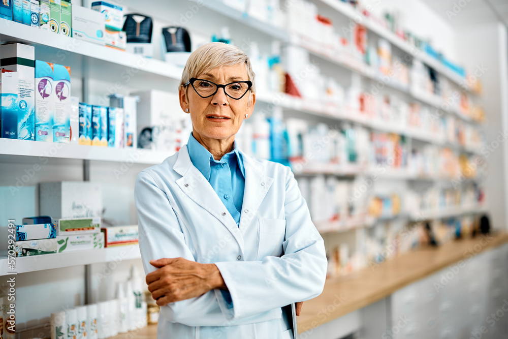 Confident senior pharmacist with her arms crossed looking at camera.
