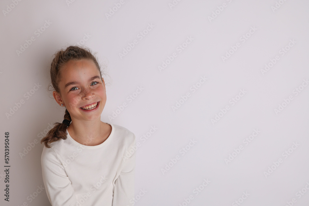 Little emotional teen girl in white shirt 11, 12 years old on an isolated white background. Children's studio portrait. Place text, to copy space for inscription, advertising children's goods. Little emotional teen girl in white shirt 11, 12 years old on an isolated white background. Children's studio portrait. Place text, to copy space for inscription, advertising children's goods.