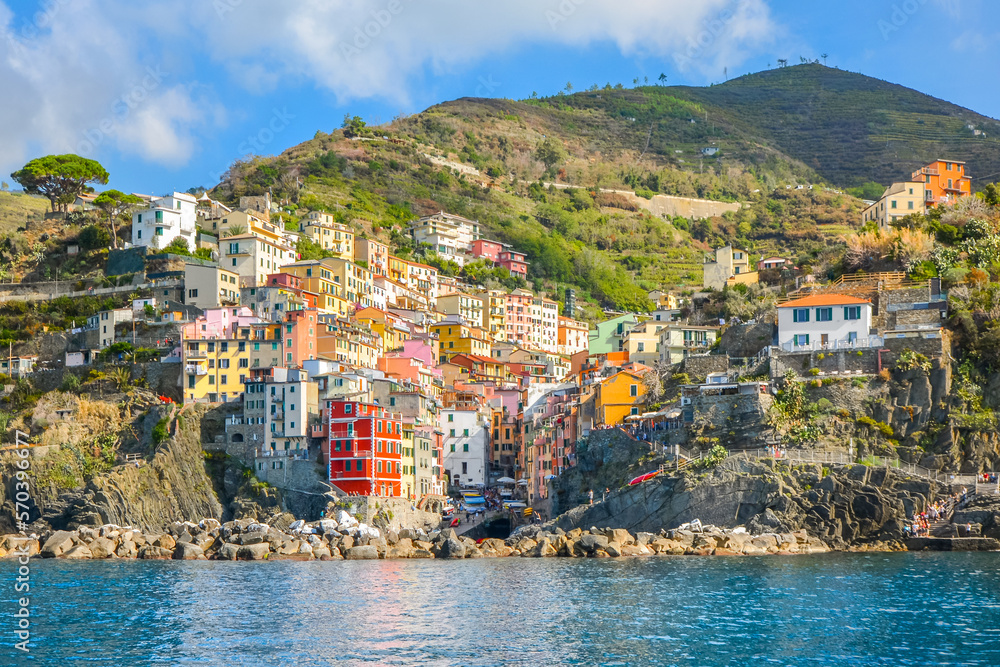 The colorful coastal and hillside village of Riomaggiore, Italy, on the Ligurian coast of the Cinque Terre in early autumn with aqua blue sea.	