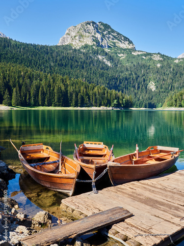 Tranquil scene of wooden rowboats moored in Black Lake. Idyllic background with a forest of trees reflecting in the water and Međed (Medjed) Peak in Durmitor National Park. Zabljak, Montenegro, Europe