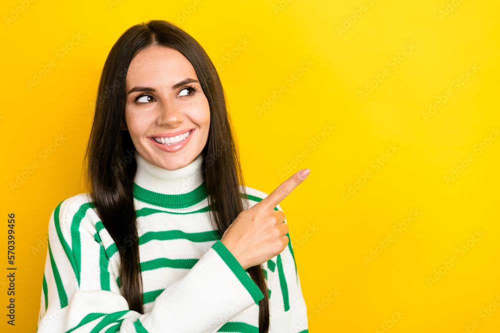 Photo of dreamy charming lady dressed striped pullover looking showing finger empty space isolated yellow color background Photo of dreamy charming lady dressed striped pullover looking showing finger empty space isolated yellow color background