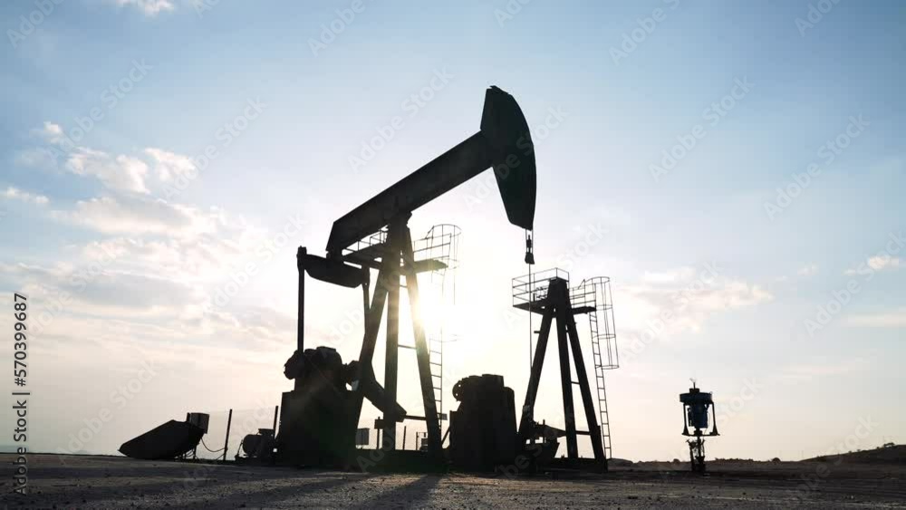 Oil worker standing among the oil pump jacks. Oil industry, crude oil prices concept. Oil worker standing among the oil pump jacks. Oil industry, crude oil prices concept.