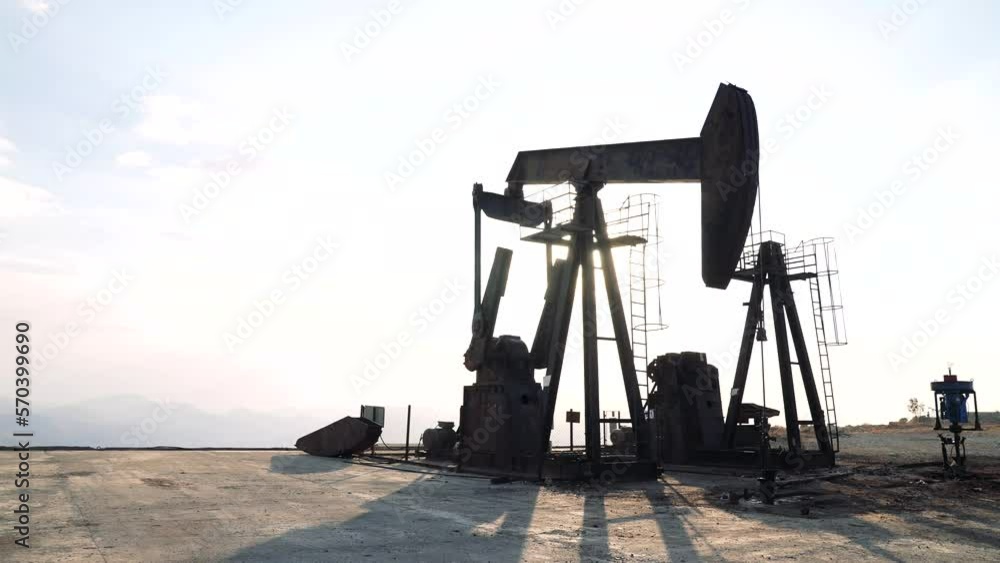 Oil worker standing among the oil pump jacks. Oil industry, crude oil prices concept. Oil worker standing among the oil pump jacks. Oil industry, crude oil prices concept.