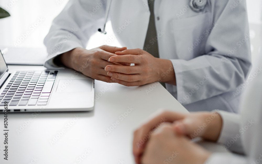 Doctor and patient discussing current health examination while sitting at the desk in clinic office, closeup. Perfect medical service and medicine concept Doctor and patient discussing current health examination while sitting at the desk in clinic office, closeup. Perfect medical service and medicine concept