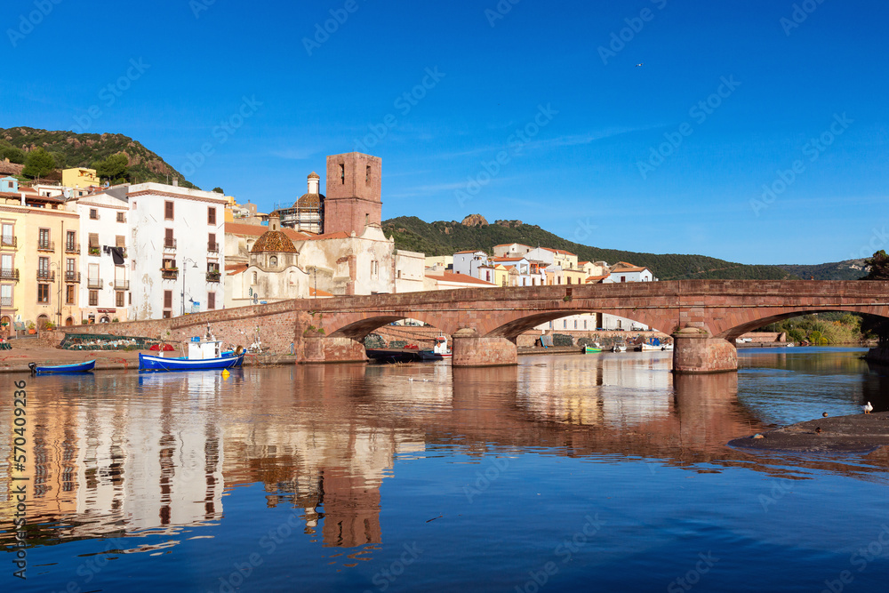 Obraz premium River with Homes and Apartments in Touristic Town. Bosa, Sardinia, Italy. Sunny Fall Season Day. Panorama