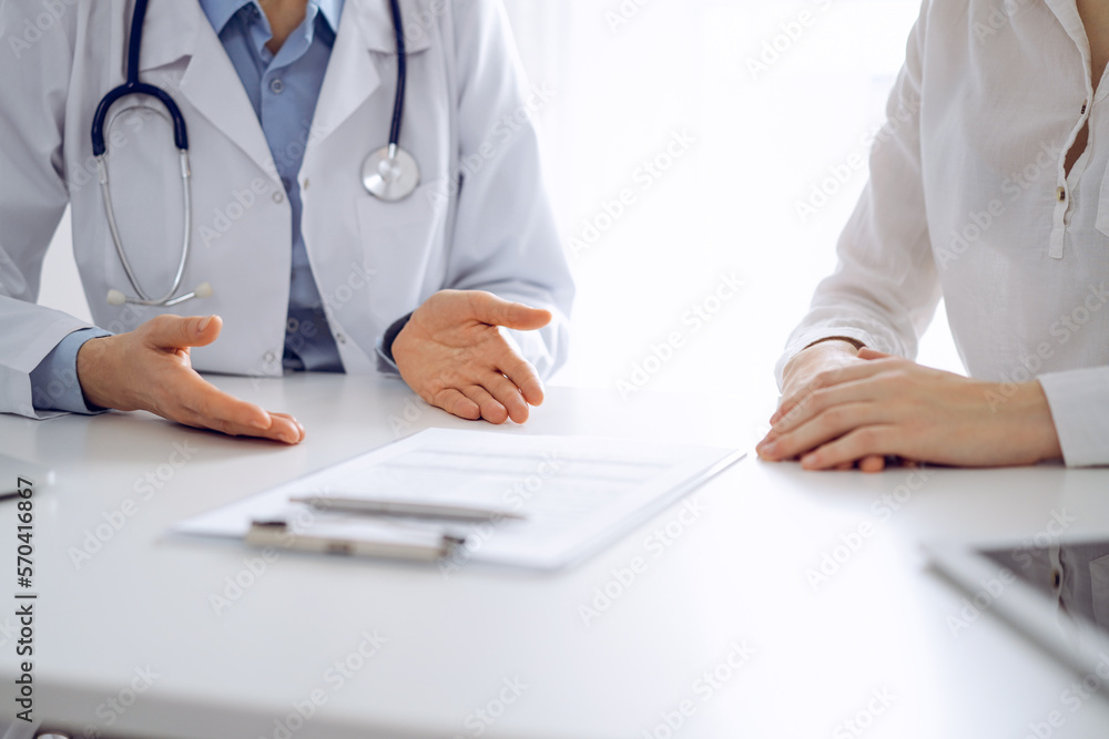 Doctor and patient discussing current health questions while sitting near of each other and using clipboard at the table in clinic, just hands closeup. Medicine concept Doctor and patient discussing current health questions while sitting near of each other and using clipboard at the table in clinic, just hands closeup. Medicine concept
