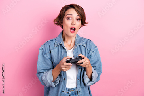 Photo of impressed cute woman wear jeans shirt plaing online game isolated pink color background