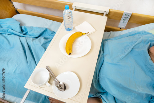 above view of dishes and banana on table on homecare electric hospital bed with patient at home photo