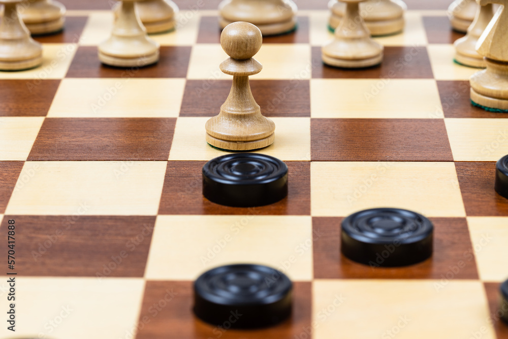 playing by different rules on the same board - black checkers and white chess figures on wooden chessboard, pawn and checkers piece in center of playfield closeup (focus on the pawn) playing by different rules on the same board - black checkers and white chess figures on wooden chessboard, pawn and checkers piece in center of playfield closeup (focus on the pawn)