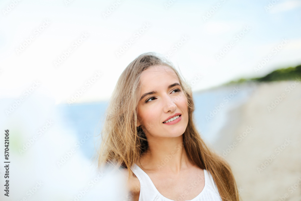 Portrait of a happy smiling woman in free happiness bliss on ocean beach enjoying nature during travel holidays vacation outdoors. View through white blurred flowers Portrait of a happy smiling woman in free happiness bliss on ocean beach enjoying nature during travel holidays vacation outdoors. View through white blurred flowers