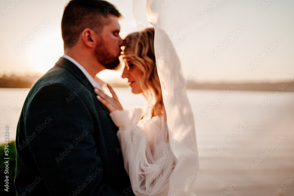 the bride and groom under the veil on the sunset by the river the bride and groom under the veil on the sunset by the river