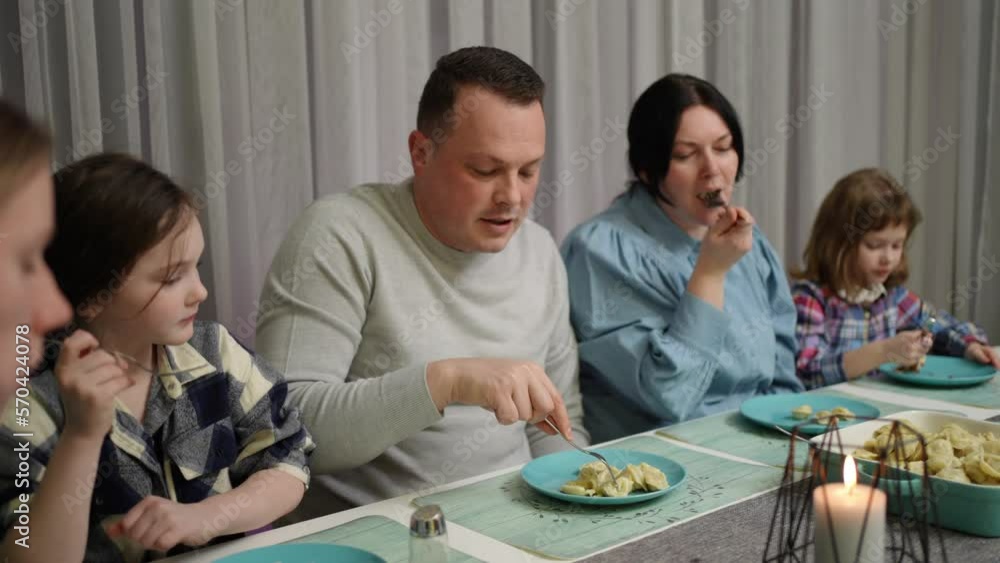 A friendly family is sitting at the table and eating dumplings A friendly family is sitting at the table and eating dumplings