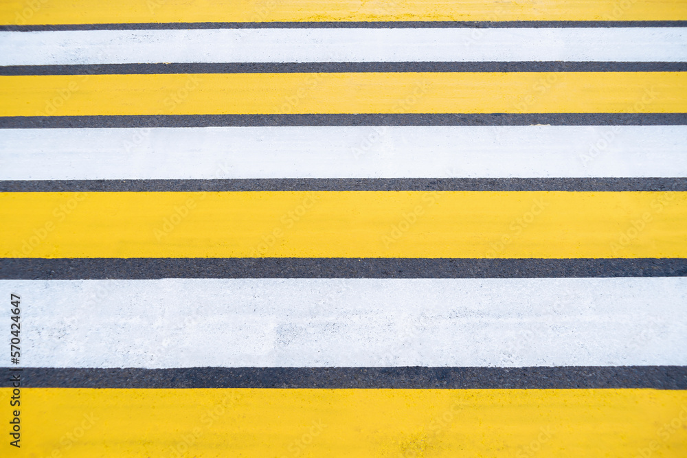 Yellow white pedestrian crossing on asphalt. Close-up of the road. Yellow white pedestrian crossing on asphalt. Close-up of the road.