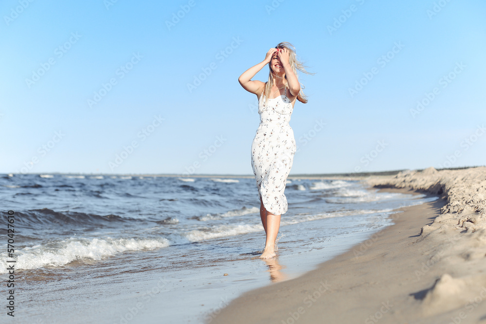 Happy blonde beautiful woman having fun on ocean beach while dancing in waves