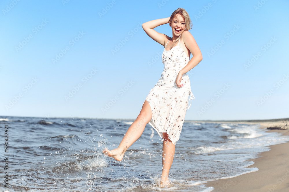 Happy blonde beautiful woman having fun on ocean beach while dancing in waves Happy blonde beautiful woman having fun on ocean beach while dancing in waves