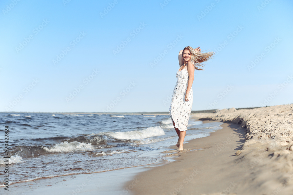 Happy blonde beautiful woman having fun on ocean beach while dancing in waves