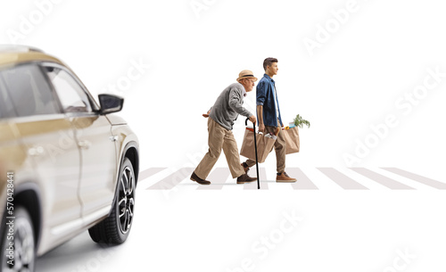 Car driving towards a young man and a senior on a pedestrian crossing