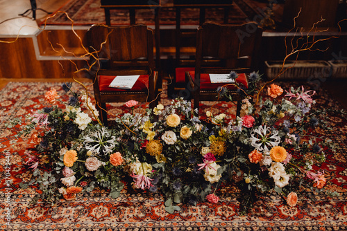 Grand bouquet de fleurs devant les chaises des futurs époux
