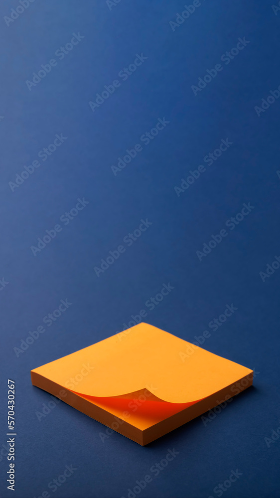 Fototapeta premium Orange blank paper office stickers with curled corners and shadow on blue bsckground Mocap. Reminder concept.