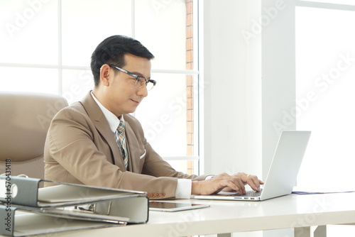 CEO Mature business man in formal clothing wearing spectacles using laptop. Serious businessman typing notebook at work. Manager in suit using zoom conference   in a modern office.