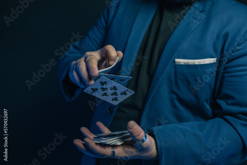 Cuadro en lienzo Close-up image of a young magician's hands in the dark dropping a deck of cards from his upper hand to his lower hand
