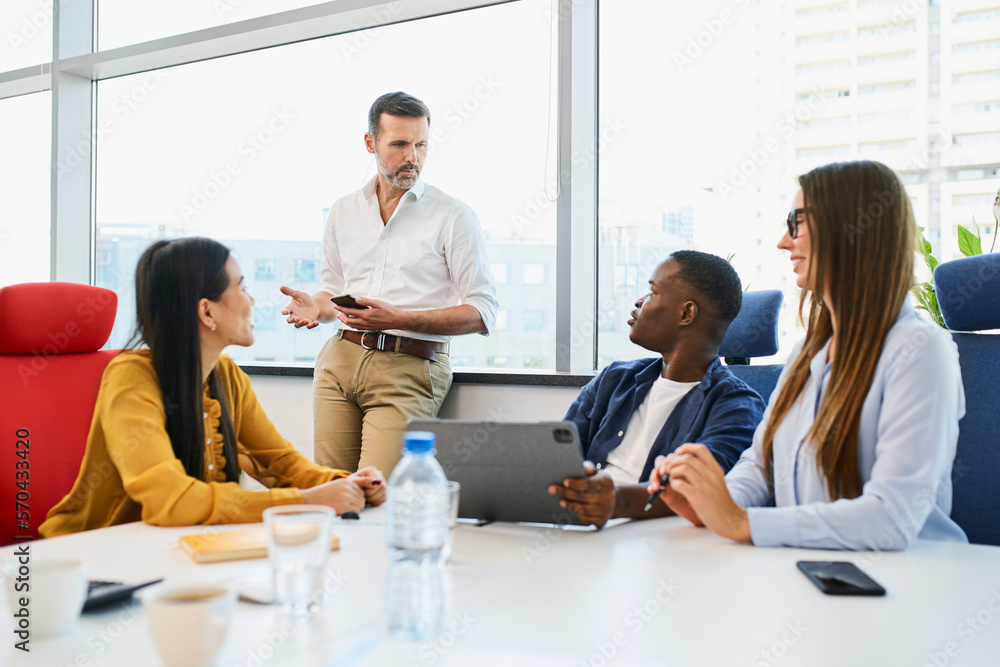 Group of diverse people discussing pitching new business ideas during casual office meeting Group of diverse people discussing pitching new business ideas during casual office meeting