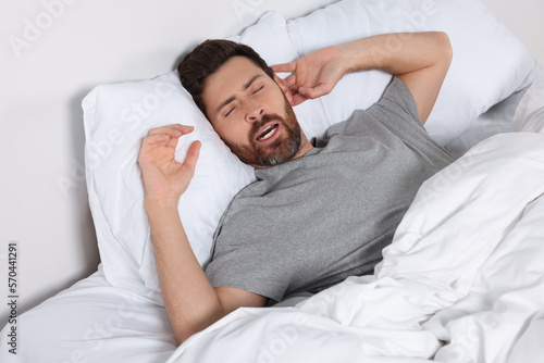 Man sleeping on comfortable pillows in bed at home