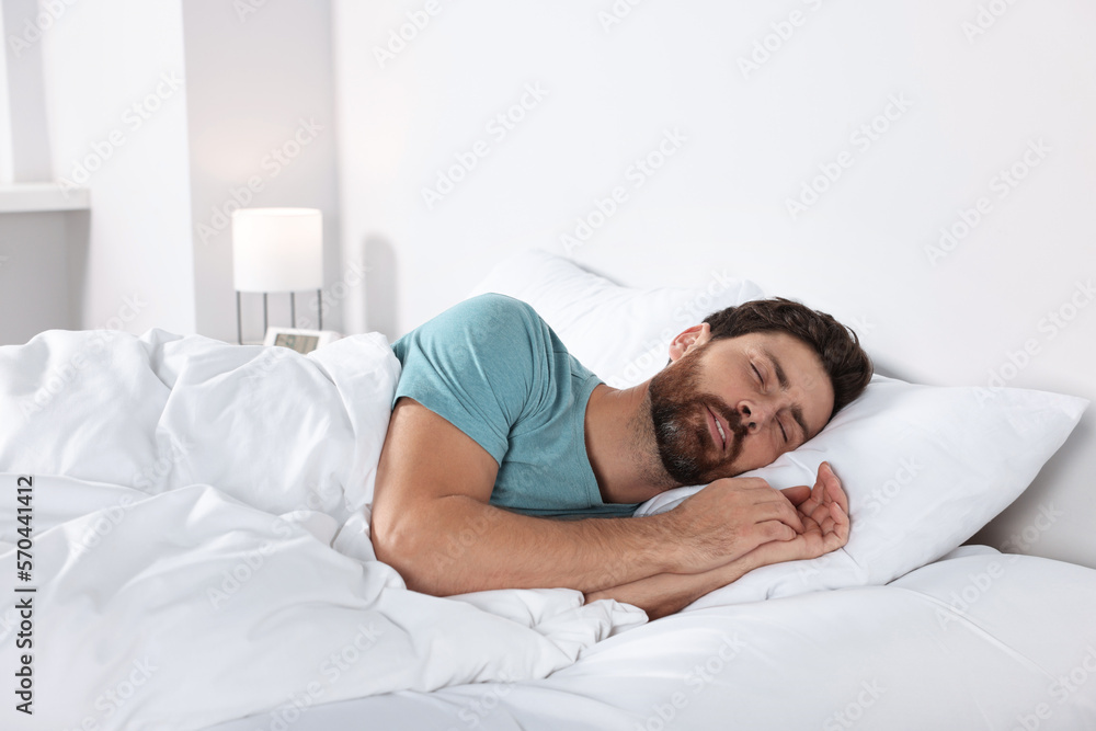Man sleeping on comfortable pillows in bed at home Man sleeping on comfortable pillows in bed at home