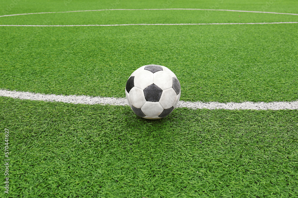 Dirty soccer ball on green football field Dirty soccer ball on green football field