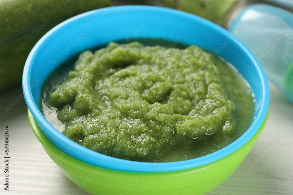 Healthy baby food. Bowl with tasty broccoli puree on white wooden table, closeup Healthy baby food. Bowl with tasty broccoli puree on white wooden table, closeup
