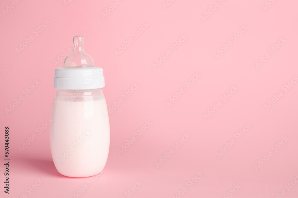 One feeding bottle with milk on pink background. Space for text One feeding bottle with milk on pink background. Space for text