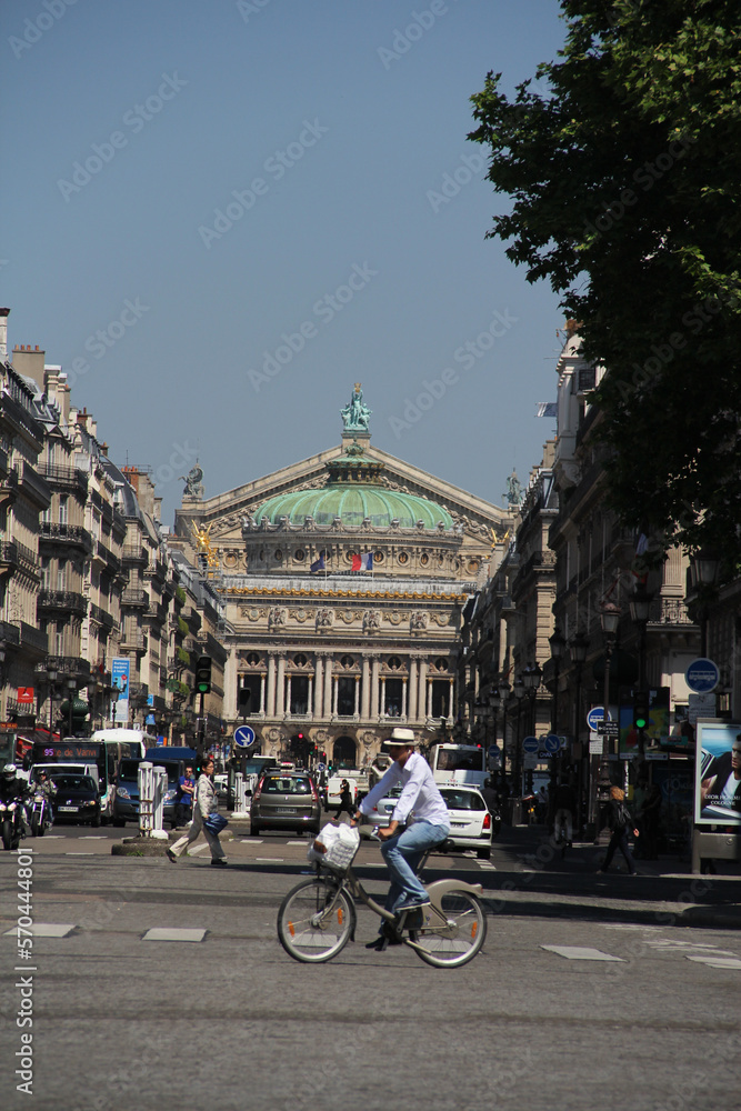 Obraz premium a cyclist through the streets of Paris with a view of the Opera Garnier in the background