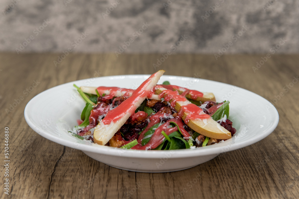 Tempting appetizer of a green salad, full of spinach, radicchio, fruit, and nuts served on a small plate Tempting appetizer of a green salad, full of spinach, radicchio, fruit, and nuts served on a small plate