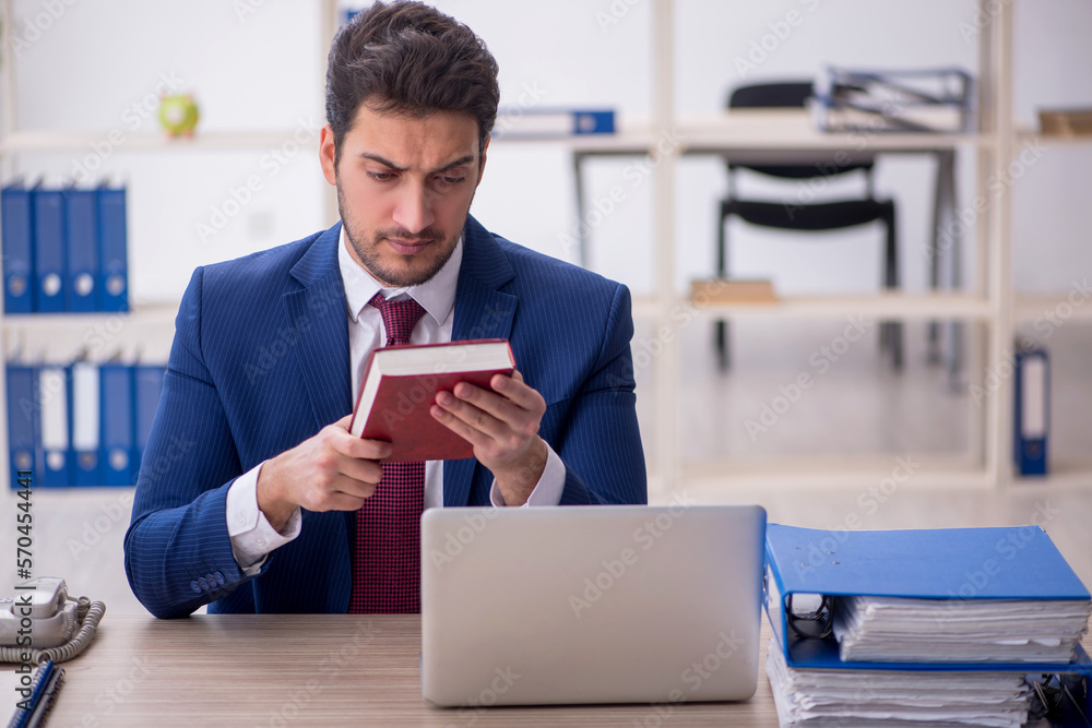 Young male employee reading book at workplace Young male employee reading book at workplace