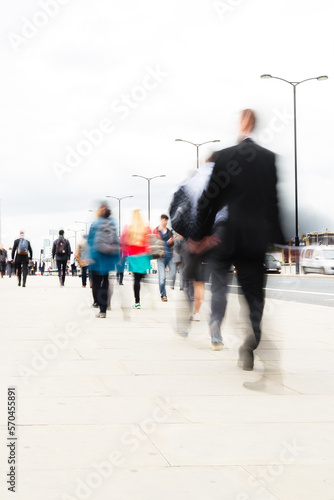 crowds of commuters walking over a bridge in London