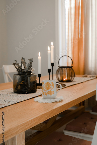 Coffee mug on the table and candles in the back