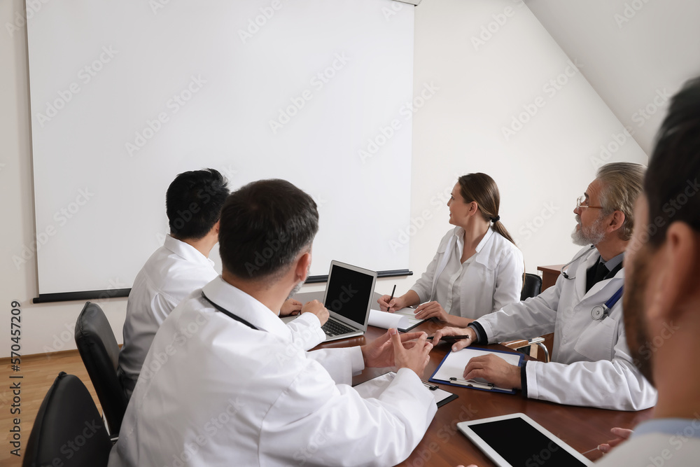 Team of doctors using video projector during conference indoors Team of doctors using video projector during conference indoors