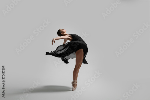 Fototapete Young ballerina practicing dance moves on light grey background