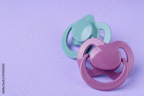 New baby pacifiers on purple background, closeup. Space for text