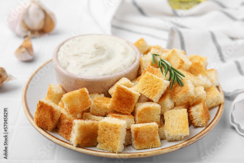 Delicious crispy croutons with rosemary and sauce on white table, closeup