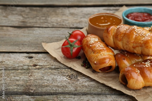 Delicious sausage rolls and ingredients on wooden table, closeup. Space for text