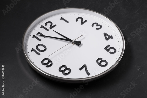 Clock showing five minutes until midnight on black table. New Year countdown