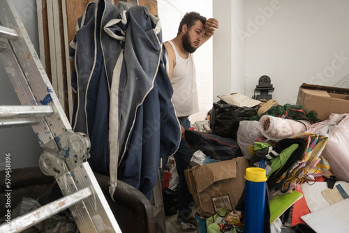 young adult man with hoarding disorder standing in a dirty room