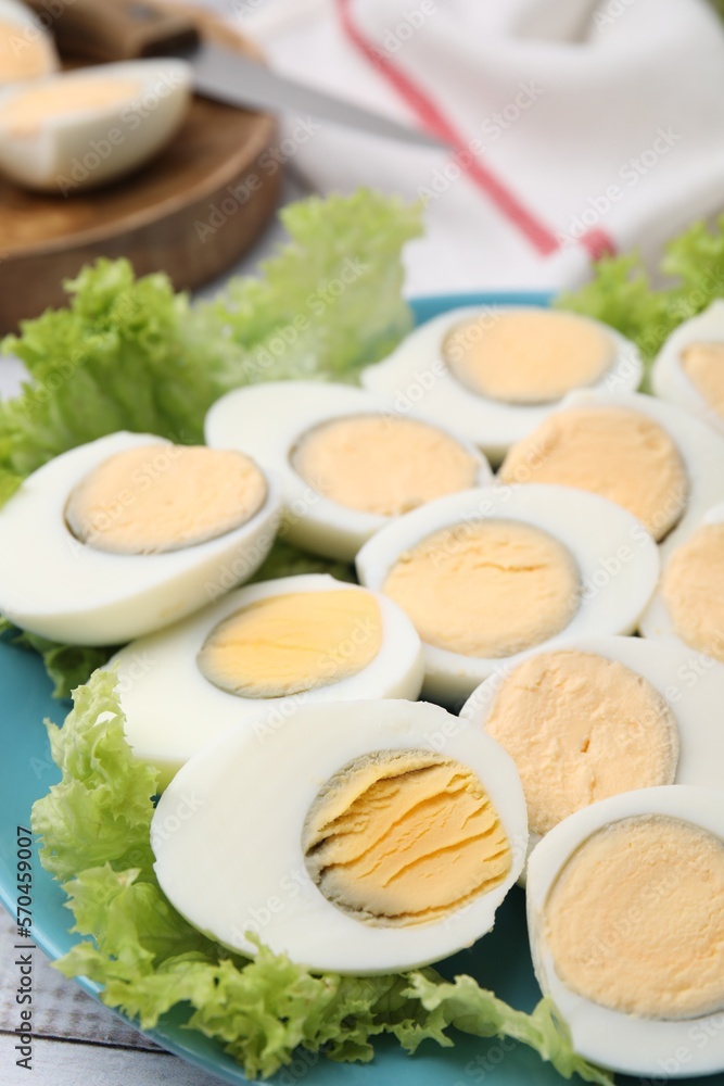 Fresh hard boiled eggs and lettuce on white wooden table
