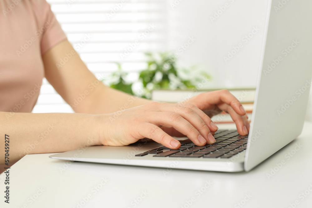 Fototapeta premium Home workplace. Woman typing on laptop at white desk indoors, closeup