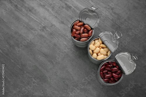 Tin cans with different canned kidney beans on grey table, flat lay. Space for text