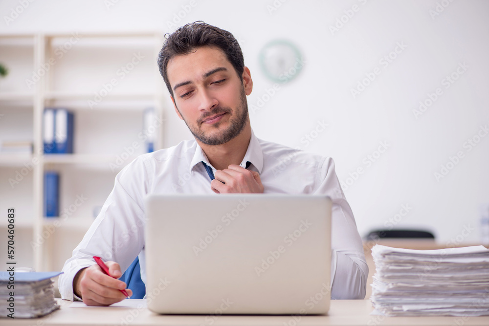 Young male employee and too much work in the office Young male employee and too much work in the office