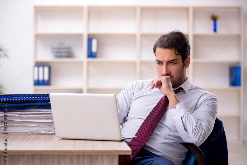 Young male employee and too much work in the office Young male employee and too much work in the office