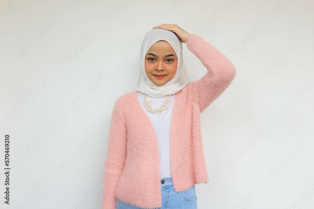 Smiling beautiful Asian woman in pink blazer and hijab looking at ...