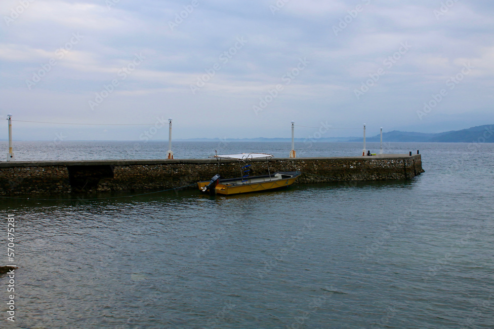 A small yellow motorboat stands in the bay near the pier.